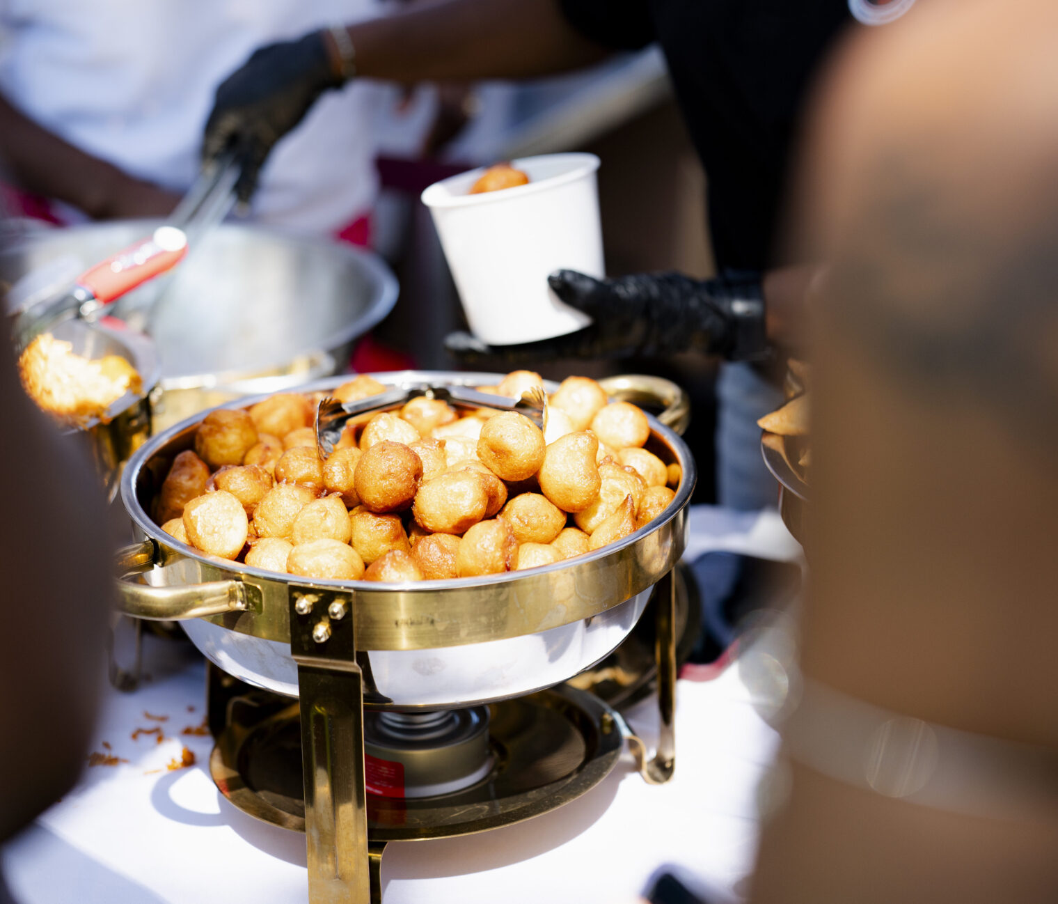 Someone is giving food to a crowd of students at the african food festival, begnets